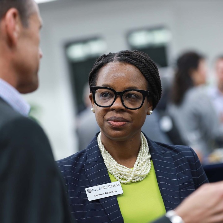 Female wearing a green blouse, pearls, and earrings, networking at a Rice University event